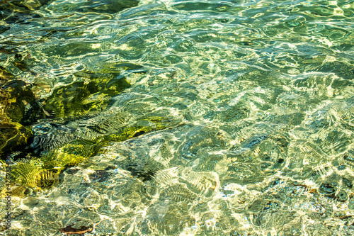 Top view of crystal clear sea water from a person's height, at a shallow coast, providing an almost abstract image.