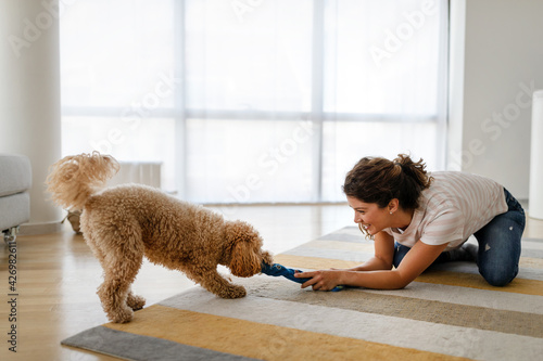 Beautiful happy woman playing with a nice cute dog at home