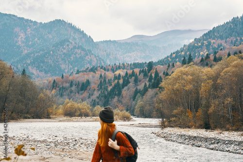 woman in a jeans sweater with a backpack rest in the mountains near the river in nature
