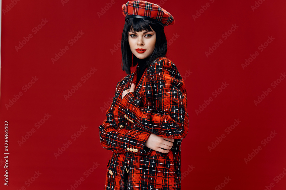 sexy brunette plaid coat and hat bright makeup red background