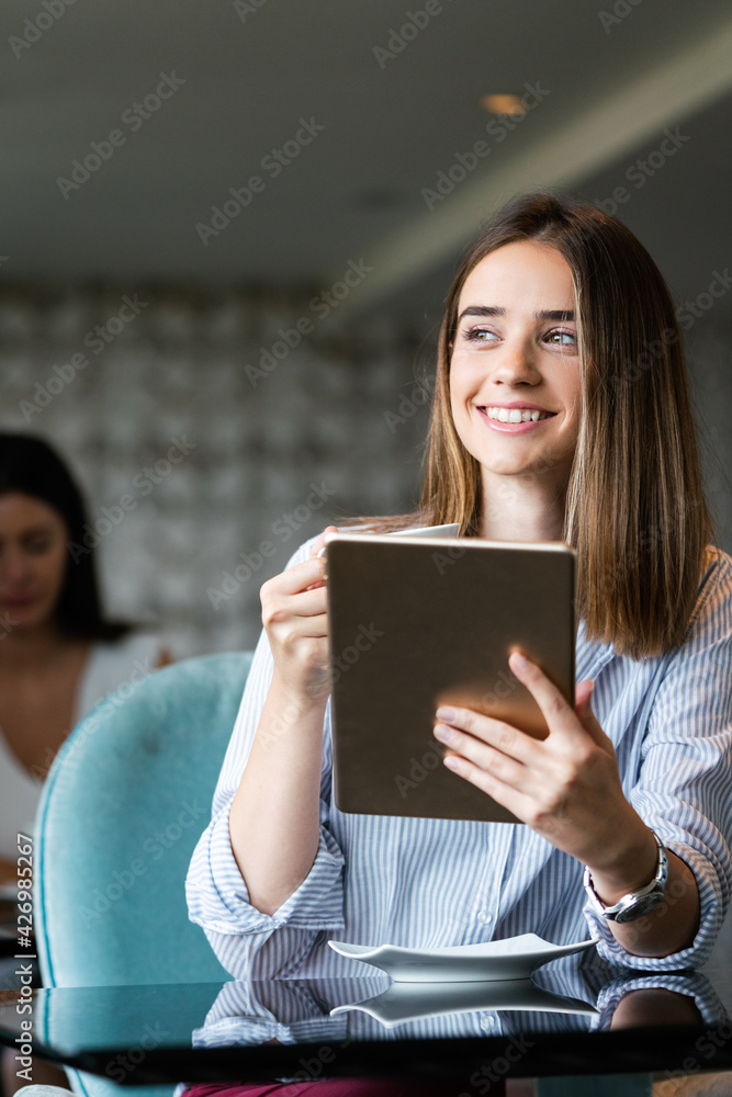 Attractive businesswoman using a digital tablet while sitting in cafe