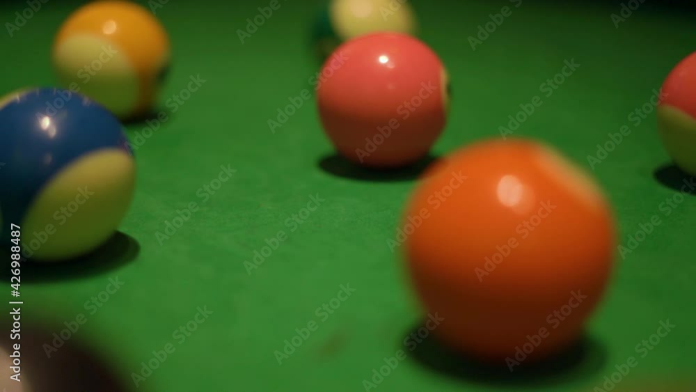 Set of colorful billiard balls with numbers lies on modern pool table covered with green velvet fabric in semi-dark bar hall extreme closeup. Set of colorful billiard balls with numbers lies on modern pool table covered with green velvet fabric in semi-dark bar hall extreme closeup.