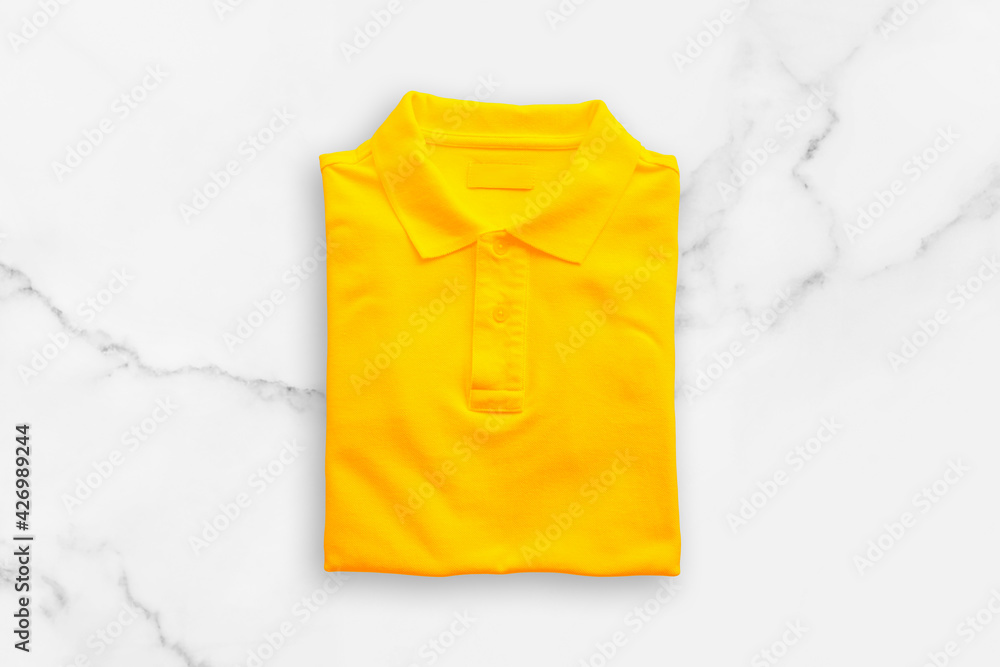 Yellow polo t-shirt on white marble floor background. Yellow polo t-shirt on white marble floor background.