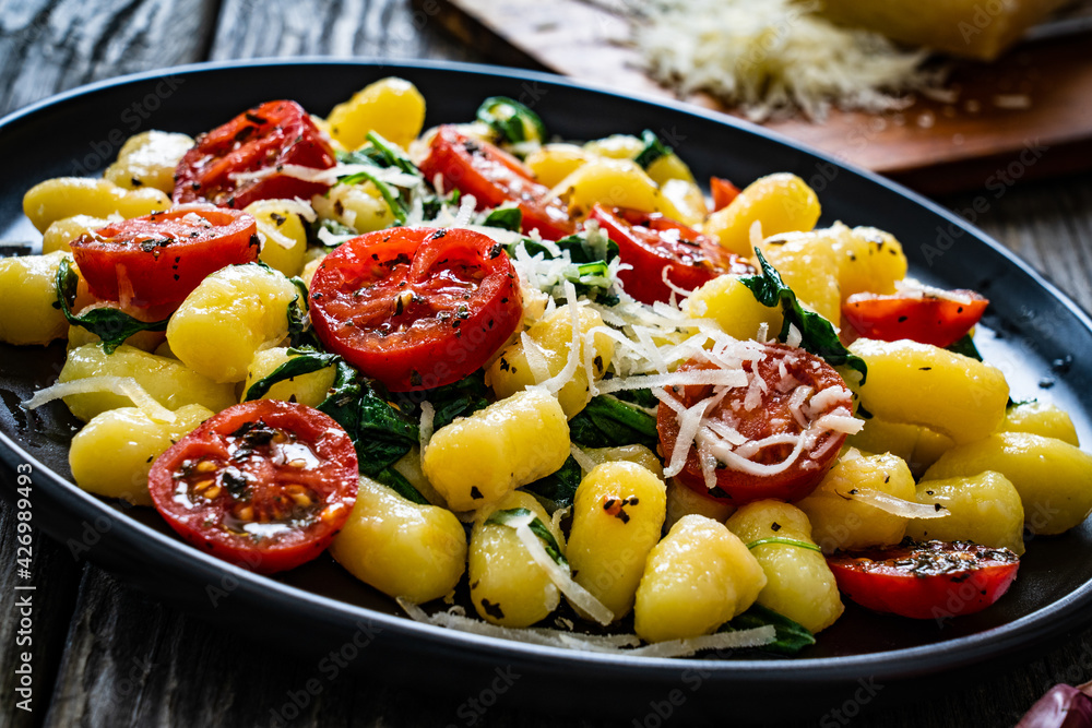 Gnocchi with tomato, spinach and parmesan  on wooden table

