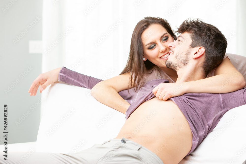 Loving young couple relaxing on a sofa in a close embrace Loving young couple relaxing on a sofa in a close embrace