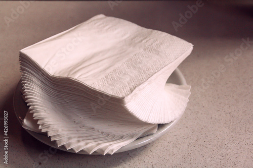 Servilletas de papel blanco. Un montón de servilletas apiladas encima de un plato. photo