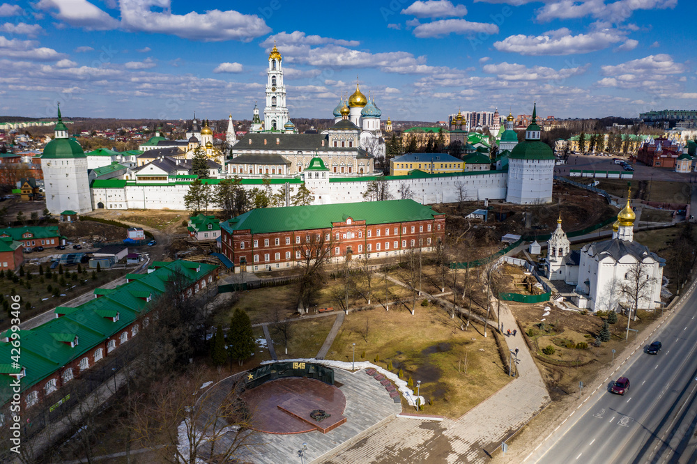 a panoramic view of the golden towers and ancient architectural solutions of the Trinity-Sergius Lavra in Sergiev Posad on a sunny spring day filmed from a drone 