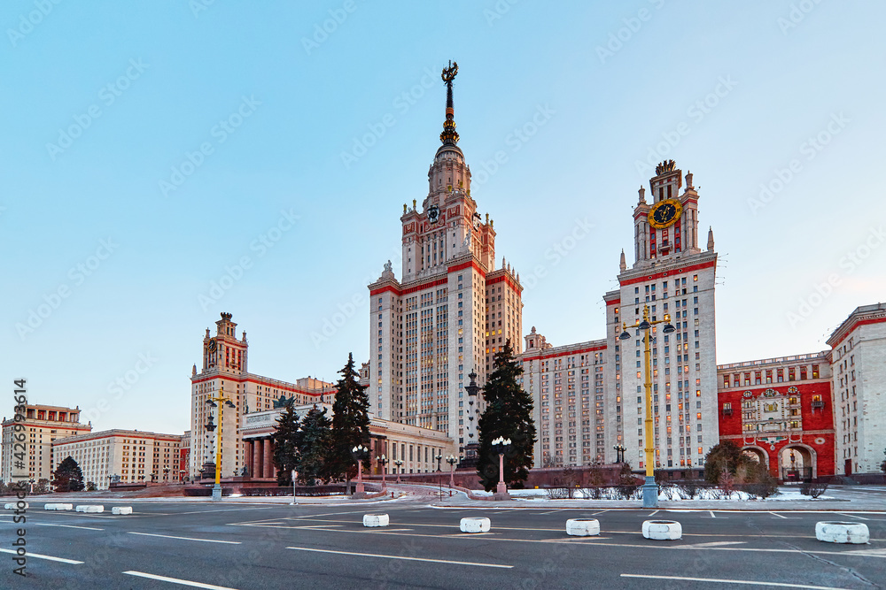 Panoramic wide angle view of spring sunset campus of Moscow university with blue sky and naked tree branches