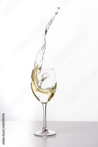 Weißwein im Weinglas mit weinspritzer aus dem glas