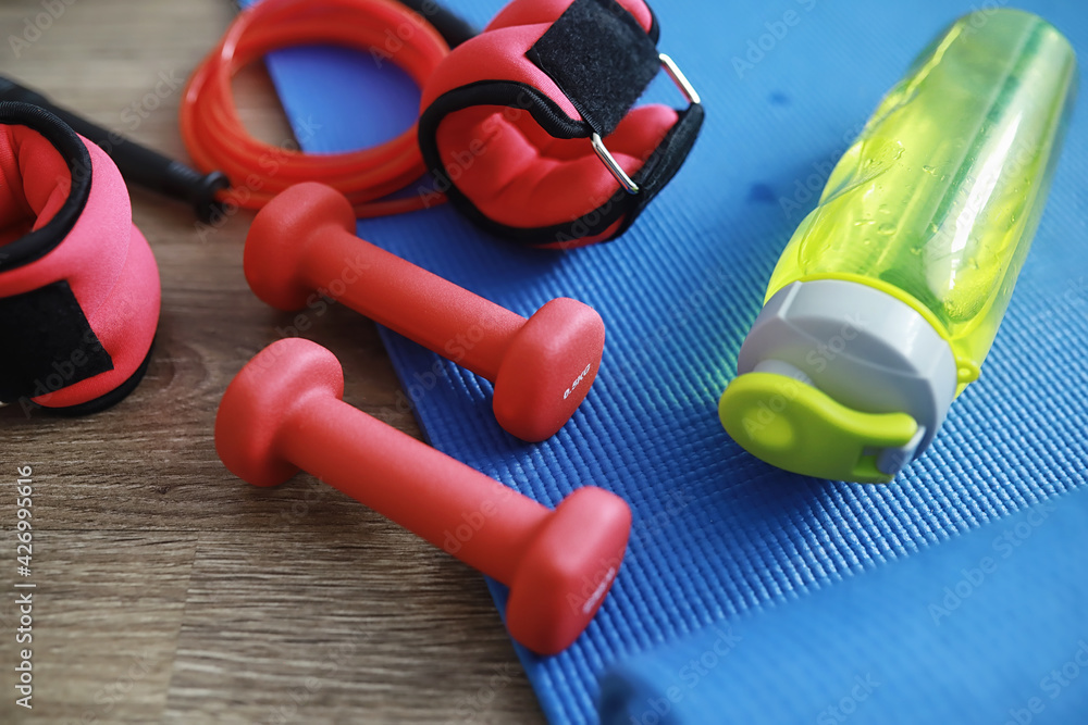 Sport and healthy lifestyle. Accessories for sports. Yoga mat dumbbell and jump rope. Sports background home exercises concept. Sport and healthy lifestyle. Accessories for sports. Yoga mat dumbbell and jump rope. Sports background home exercises concept.