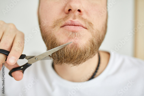 Handsome man in white t-shirts cutting beard, moustache personally himself