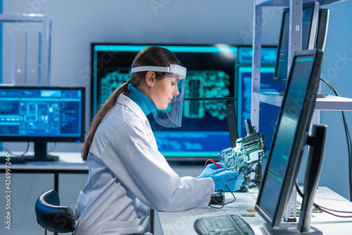 Fotografie Female microelectronics engineer works in a scientific laboratory on computing systems and microprocessors