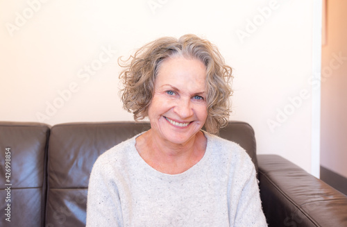Portrait of beautiful senior woman with blue eyes sitting on couch (selective focus)