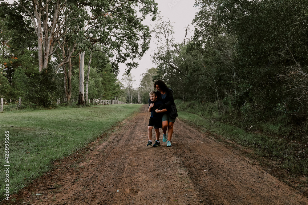 Mother and son walking happily together on country road Mother and son walking happily together on country road