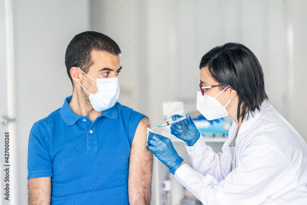 Man receiving covid 19 vaccine jab at vaccination centre Man receiving covid 19 vaccine jab at vaccination centre