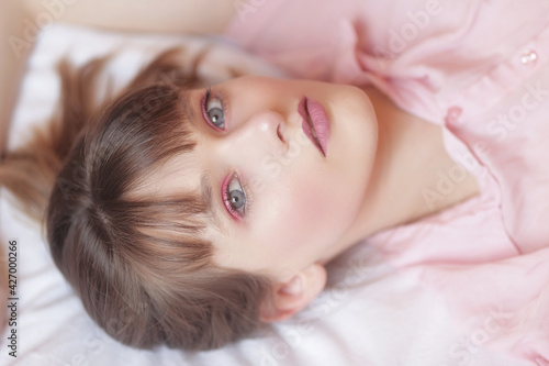 Portrait beauté d'une adolescente aux yeux bleu allongée sur un lit