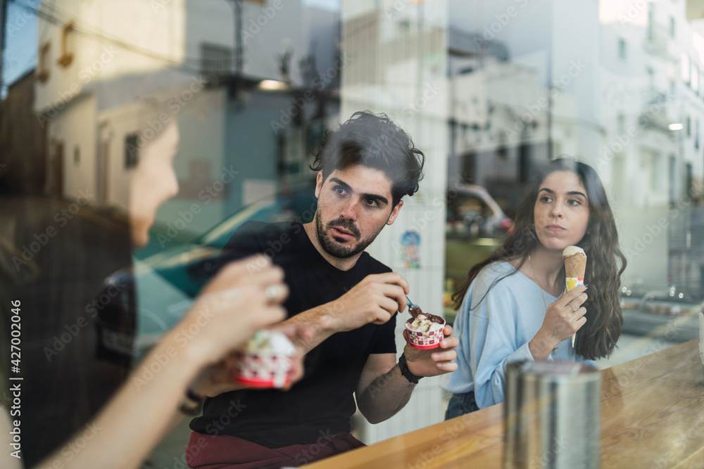 Amigos chicos y chicas tomando helado en la barra interior de una heladeria Amigos chicos y chicas tomando helado en la barra interior de una heladeria