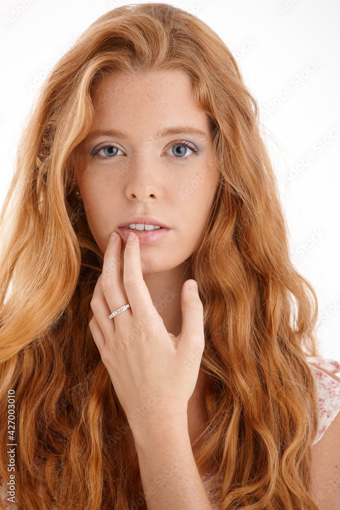 Pretty redhead portrait, closeup face and hand, touching lips, looking at camera, beautiful long red curly hair. Pretty redhead portrait, closeup face and hand, touching lips, looking at camera, beautiful long red curly hair.