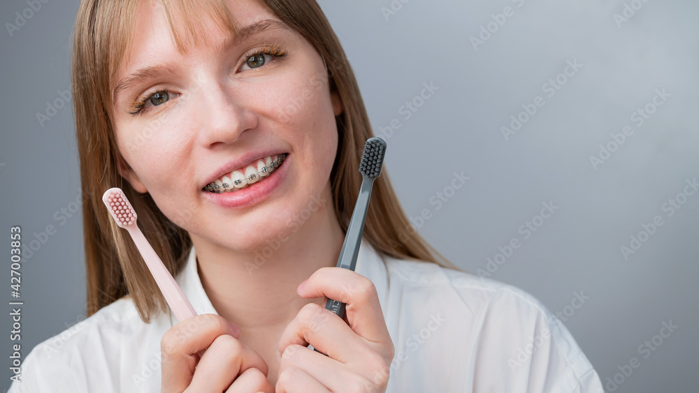Caucasian woman in braces holding toothbrushes on white background. Caucasian woman in braces holding toothbrushes on white background.