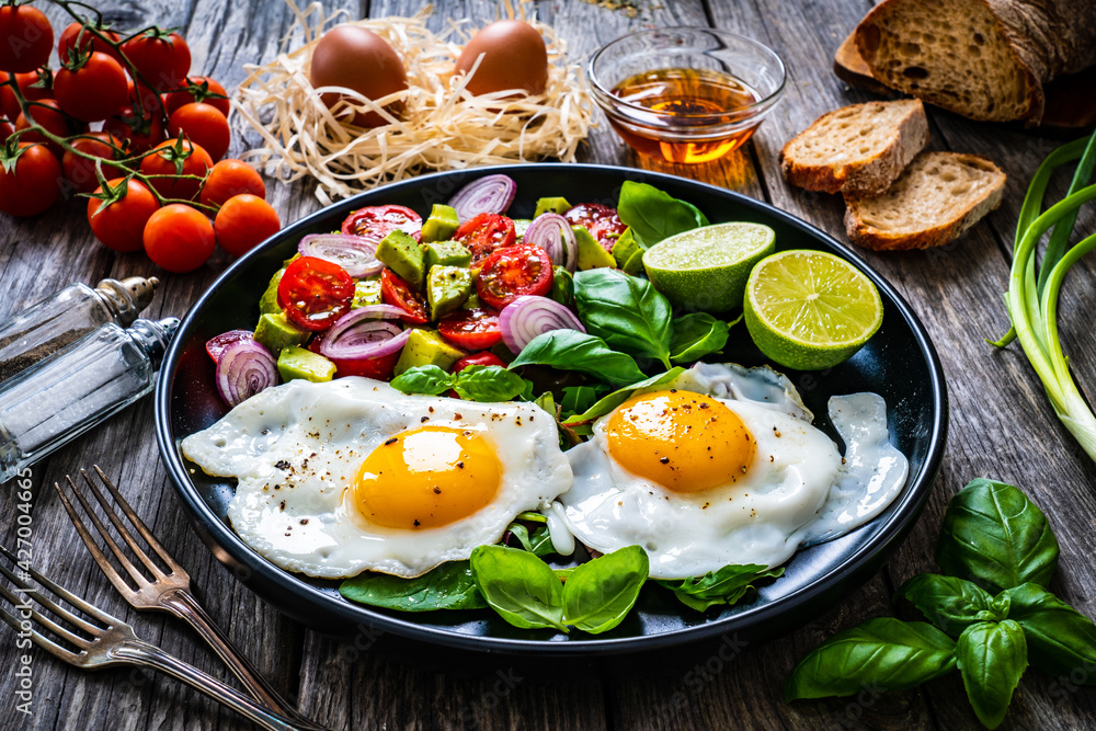 Sunny side up eggs with avocado, cherry tomatoes, toasted bread and red onion on wooden table
Sunny side up eggs with avocado, cherry tomatoes, toasted bread and red onion on wooden table