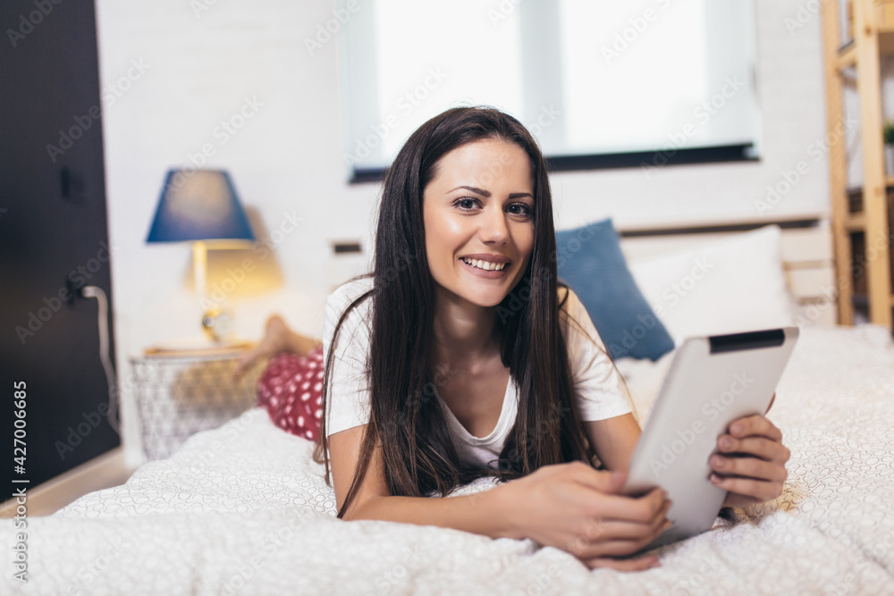 Young woman relaxing and using digital tablet computer in the bed at home Young woman relaxing and using digital tablet computer in the bed at home