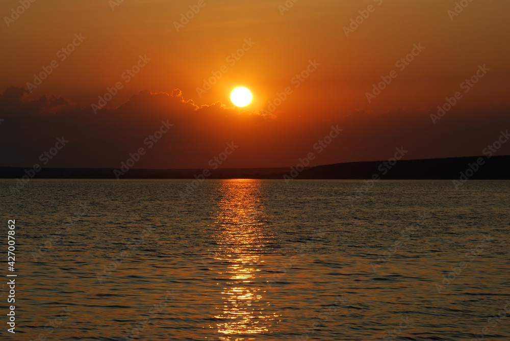 The setting sun is reflected in the water