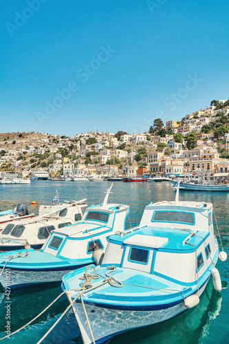 Moored motorboats on azure sea with reflection against city