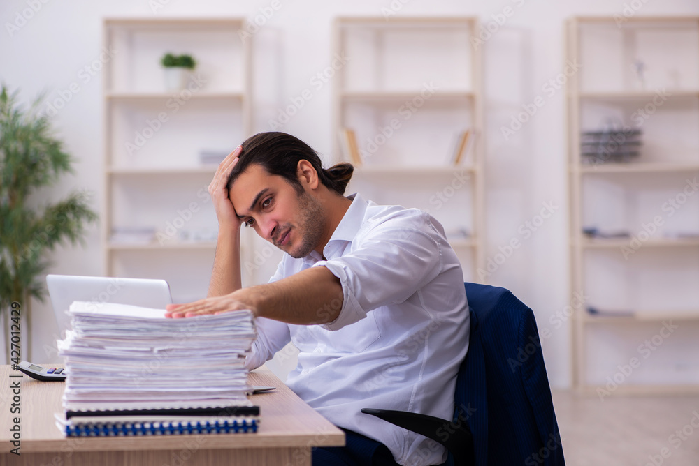 Obraz premium Young businessman employee unhappy with excessive work in the office