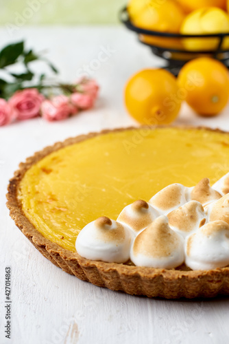 Tart with lemon curd with merenga decor on a light wooden background.