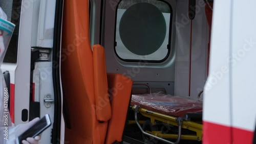 Female doctor Wearing a Transparent Protective Face Shield, Mask and Overalls at the Covid-19 gets into ambulance car. Ambulance crew gets into transport, ready to save lives, responds to call out.