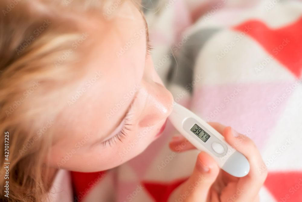 Sick teenage girl sitting on the bed covered with blanket measure body temperature Sick teenage girl sitting on the bed covered with blanket measure body temperature