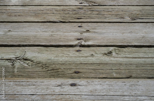 Five old wooden planks with rusty nails. The view is at an angle creating perspective. 