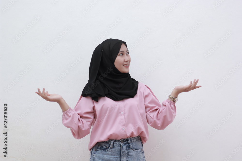 Portrait of young muslim girl in hijab felt confused in making two choices. over white background. Beautiful asian woman with casual dress. Beautiful muslim women. Portrait of young muslim girl in hijab felt confused in making two choices. over white background. Beautiful asian woman with casual dress. Beautiful muslim women.