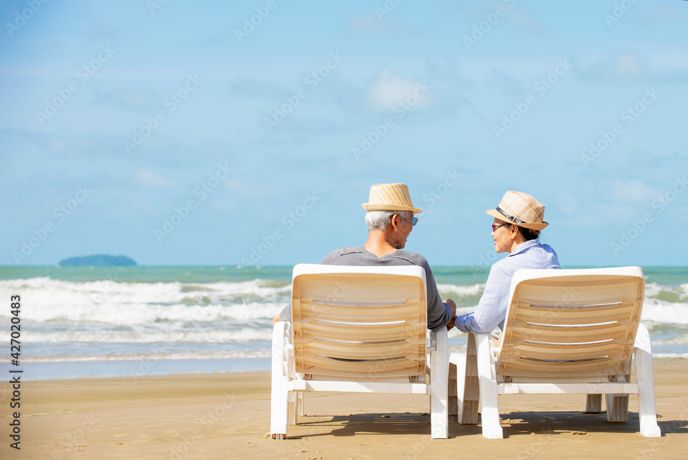 Relax  asian senior couple in sun hat  sitting on beach chair at  beach looking sea viwe  enjoy life