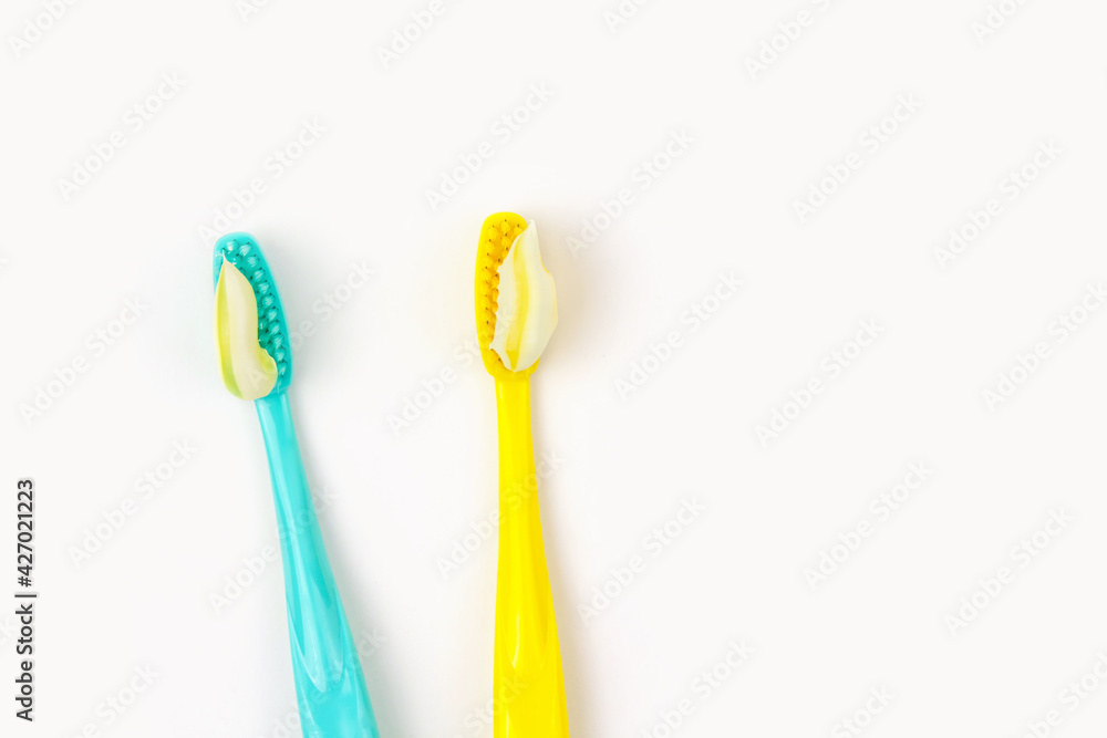 Blue and yellow toothbrushes with yellow striped paste on white isolated background. Blue and yellow toothbrushes with yellow striped paste on white isolated background.