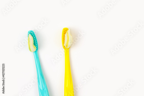 Blue and yellow toothbrushes with yellow striped paste on white isolated background.