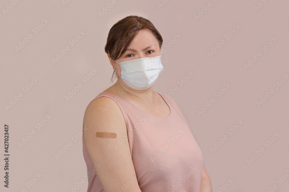 Portrait of a woman after vaccination on a pastel background with copy space. Middle-aged woman with forearm bandage after vaccination