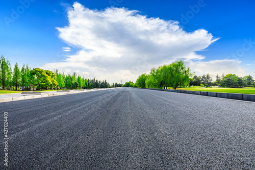 Empty asphalt road and green trees in spring season.