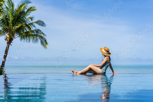Young woman traveler relaxing and enjoying by a tropical resort pool while traveling for summer vacation, Travel concept © Kittiphan