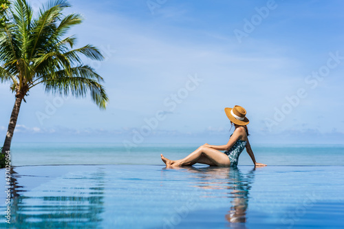 Young woman traveler relaxing and enjoying by a tropical resort pool while traveling for summer vacation, Travel concept