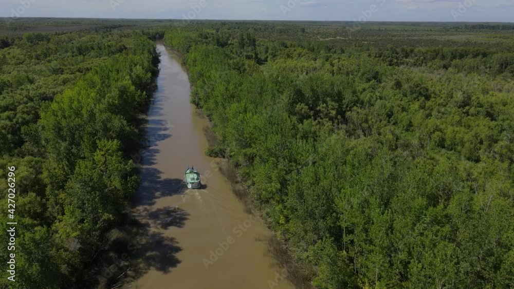 Cargo ship boat navigating narrow river in sunny day with rainforest Cargo ship boat navigating narrow river in sunny day with rainforest