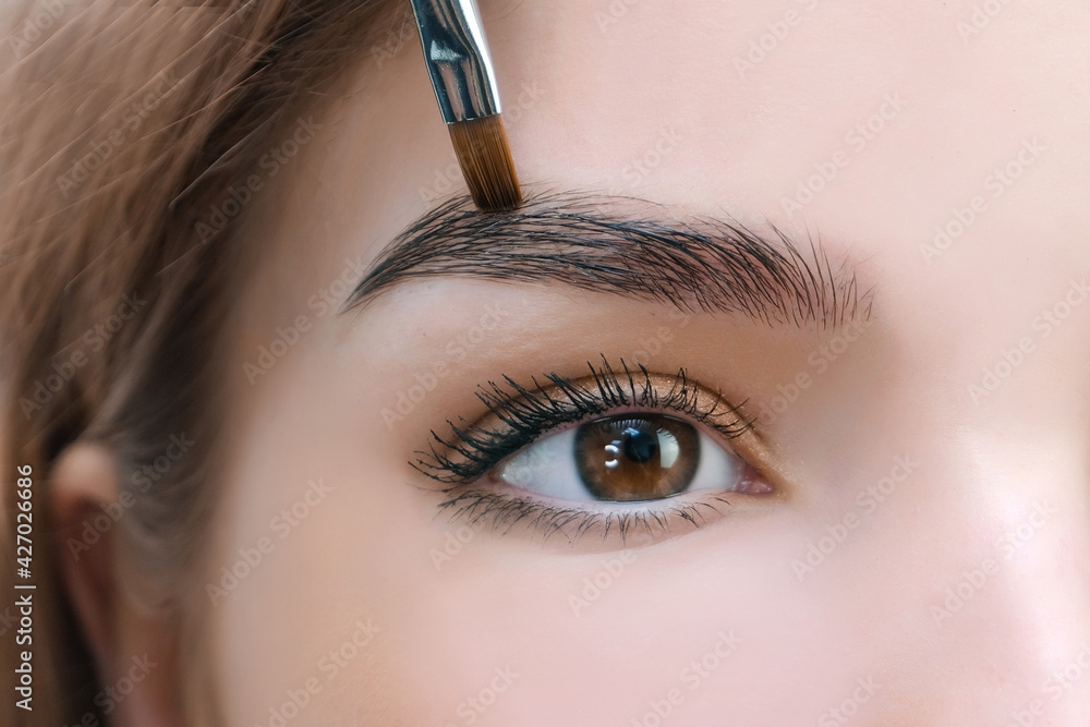 Naklejka premium Young woman shaping eyebrows with brush
