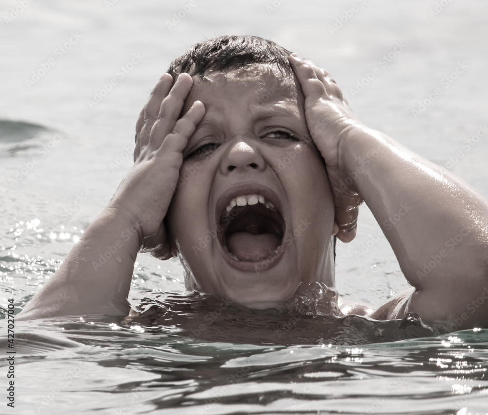 Boy shouts in the water of the sea. Horror emotion