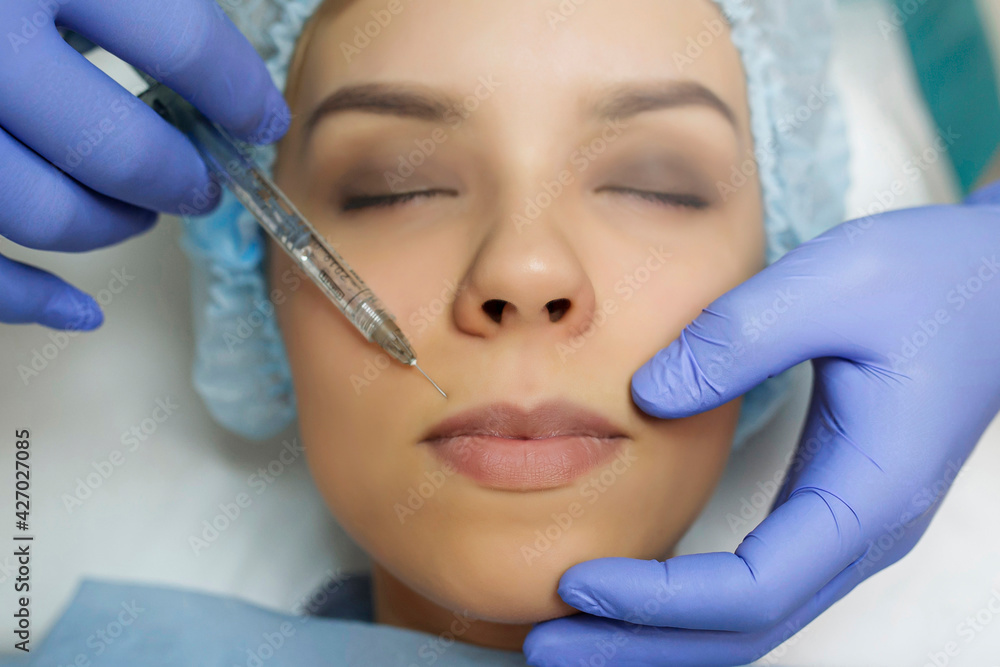 Close up cosmetologist hands in gloves introducing Hyaluronic acid in patient lips with perfect skin. Close up cosmetologist hands in gloves introducing Hyaluronic acid in patient lips with perfect skin.