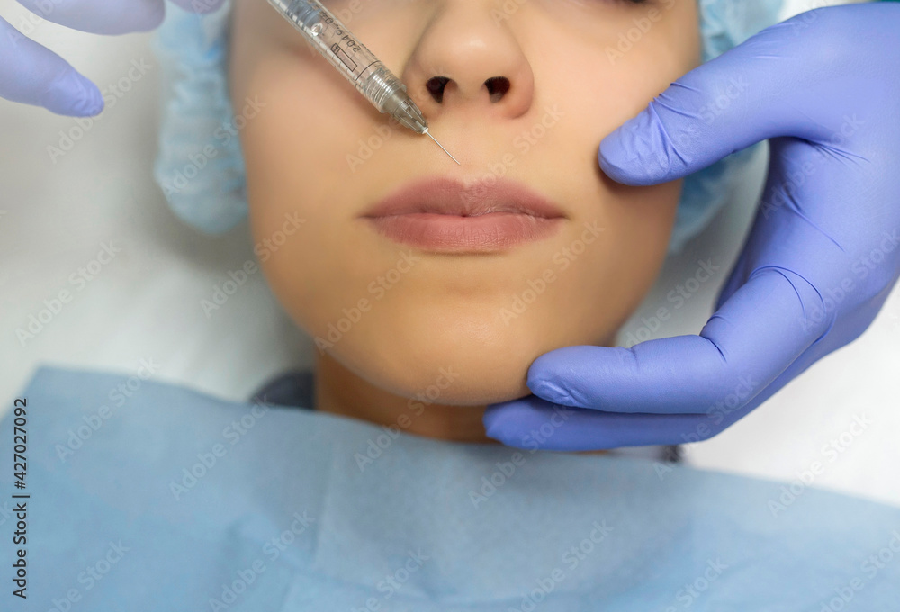 Close up cosmetologist hands in gloves introducing Hyaluronic acid in patient lips with perfect skin.