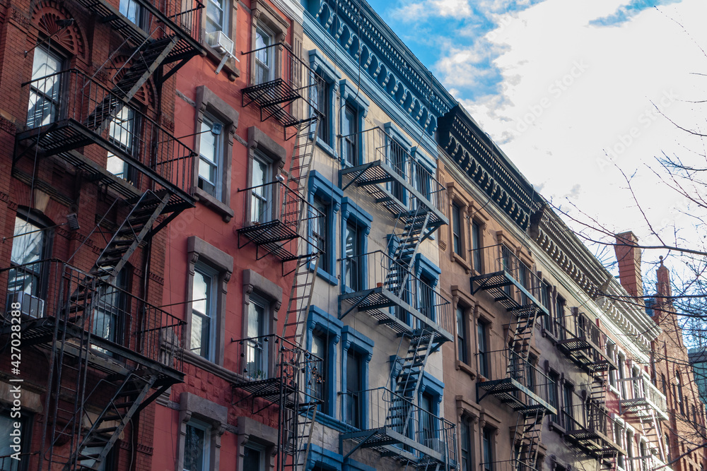 Row of Colorful Old Brick Apartment Buildings in Greenwich Village of New York City with Fire Escapes