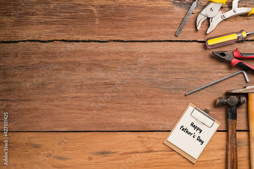 Happy Fathers Day text with side border of tools and ties on a rustic wood background