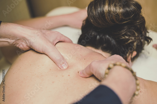 Soft focus view of man massaging a woman in a wellness center Oiled hands on a body relaxing the muscles and relieve tension .Holistic exercise for calm and clear your mind. Health well-being concept