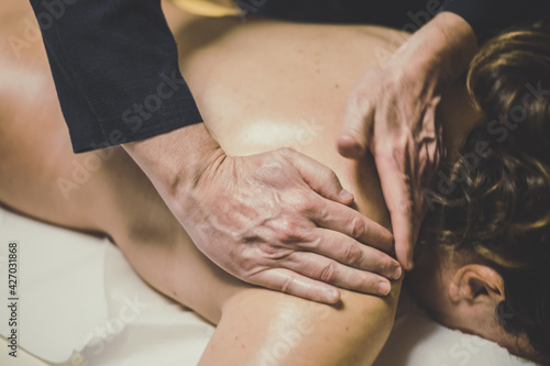 Soft focus view of man massaging a woman in a wellness center Oiled hands on a body relaxing the muscles and relieve tension .Holistic exercise for calm and clear your mind. Health well-being concept