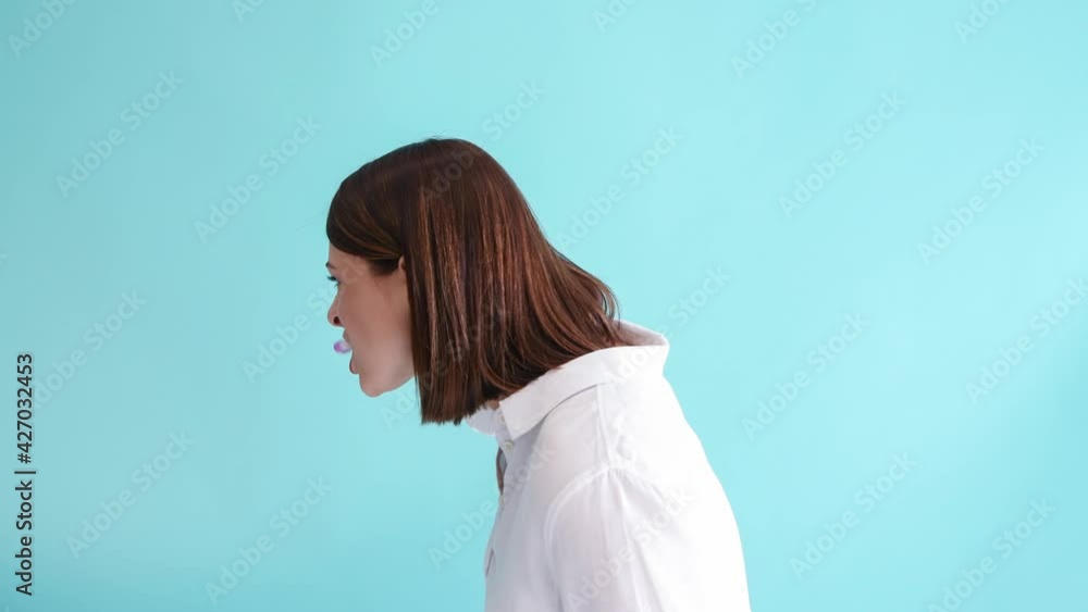 Beautiful caucasian woman in white shirt brushes teeth with manual purple toothbrush and then smiles. Blue background. 4K resolution video. Dental Health Theme. Beautiful caucasian woman in white shirt brushes teeth with manual purple toothbrush and then smiles. Blue background. 4K resolution video. Dental Health Theme.